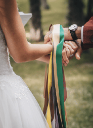 Rubans coloré autour des mains enlacées de mariés