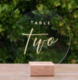 Disque transparent avec inscription doré du numéro de table disposé sur un socle en bois